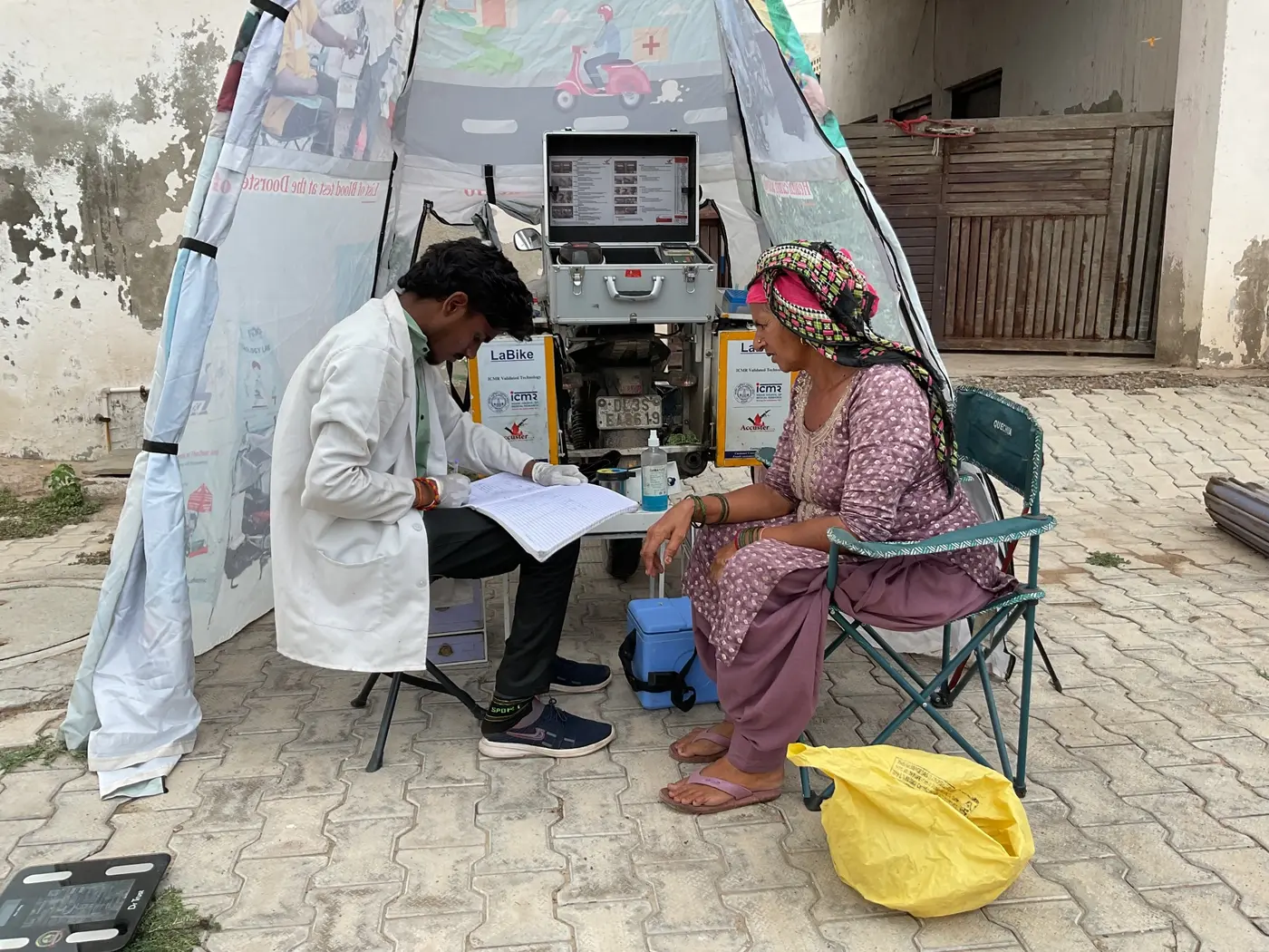 Health worker performing a diagnostic check for a woman seated outdoors